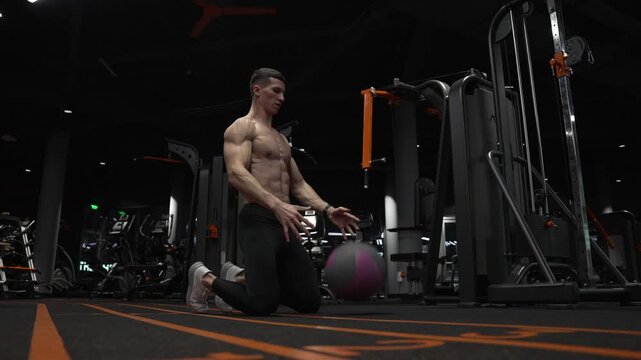 Sportsman do workout in fitness gym. Muscular man throw fitness ball on gym floor. Ball curl. Fit man ball workout in fitness gym. Fitness workout of sportsman with ball in gym