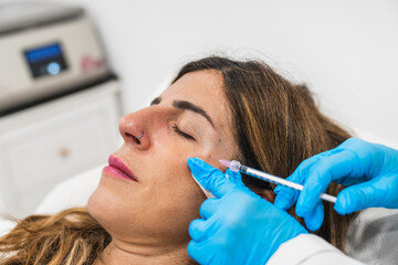 Woman getting a cosmetic injection on her face from a gloved professional for wrinkle reduction and anti-aging at a clinic