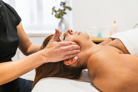 Physiotherapist performing a therapeutic massage on a woman's temporomandibular joint, treating jaw pain and promoting wellness