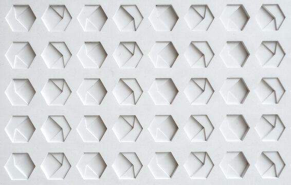 a white, textured surface featuring a grid of hexagonal indentations. Each hexagon has a three-dimensional, geometric design with internal triangular and rectangular patterns