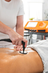 Therapist performing radiofrequency treatment on a client's back, stimulating collagen and elastin for skin regeneration and improved circulation