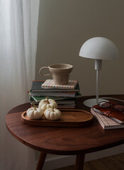 Cozy still life - books, a table lamp, autumn decor, white pumpkins on a wooden table
