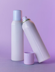 Two spray deodorant bottles on purple isolated background, mockup
