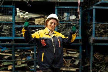 Portrait of technician women worker stand, looking camera happy smiling in garage scrap yard car workshop warehouse.
