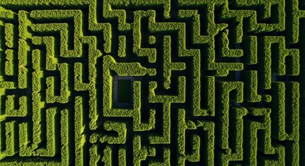 Aerial drone view of a dense green hedge maze with intricate pathways and a central square opening