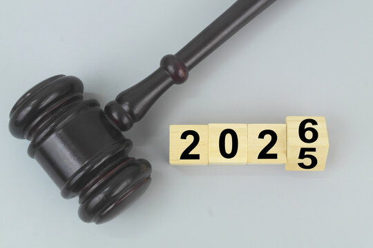 Judge gavel and flipping numbers 2025 and 2026 on cubes on grey background. Changing in laws in 2026 concept.