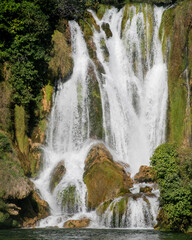 Fototapeta premium Kravitsa Cascading waterfall whispers enchantment, water sprites celebrate Misty Falls Day, natures frothy symphony in lush forest embrace