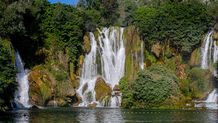 Obraz premium Lush emerald curtains cascade down rocky cliffs in a serene symphony, evoking nature's zen garden and World Water Day tranquility