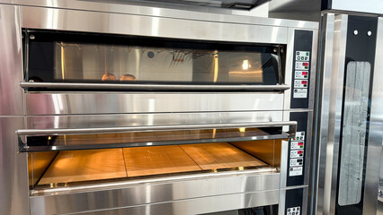 Gleaming industrial pizza oven awaits Doughnut Day delights, echoing midnight bakers' symphony with warm, aromatic whispers of anticipation
