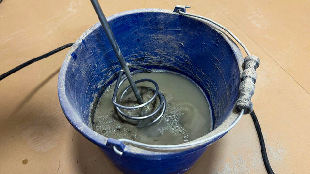 Electric whisk whirls muddy concoction, alchemizing cement during Canadian Self-Built Homes Day, blending DIY aspirations and nostalgia