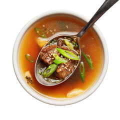 Broth, meat, scallions on spoon in bowl, top-down shot