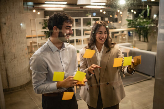 Business colleagues brainstorming ideas on glass wall