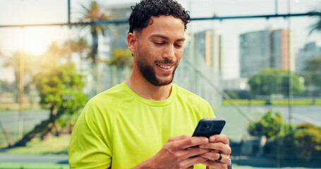 Phone, fitness and man on tennis court with networking, communication or texting on mobile app. Technology, sports and athlete with typing on cellphone for chatting, contact or social media outdoor. © peopleimages.com
