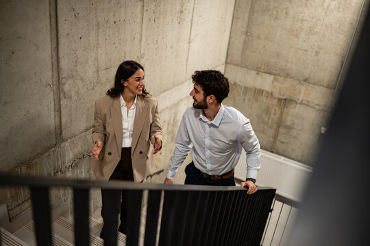 Business colleagues talking walking up office stairs
