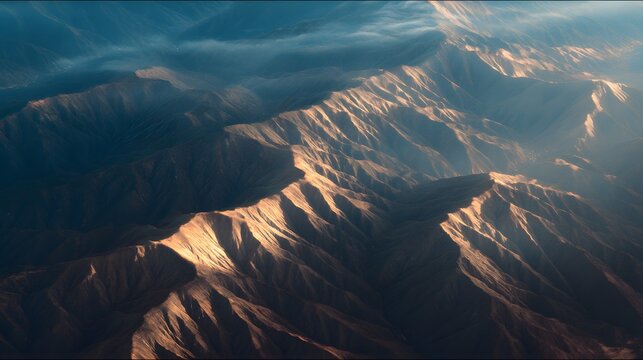 Mountain ranges are illuminated by sunlight from an aerial view.