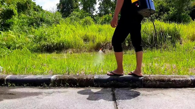 Man spraying herbicide on roadside grass for weed control, environmental maintenance concept