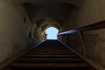 Old Wooden Staircase in Historic Building with Arched Ceiling and Light at the End