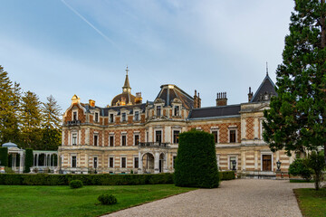 Elegant Historic European Mansion with Ornate Architecture and Lush Garden under Clear Blue Sky