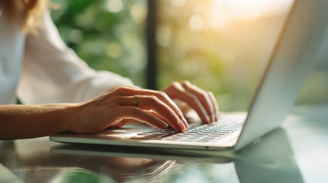 Woman's hands typing on a laptop keyboard with a ring on her finger female - Powered by Adobe
