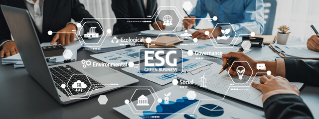 A diverse business team collaborates on environmental, social, and governance strategies, utilizing digital infographics and data presentations in a modern office setting. Amity