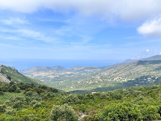 Fototapeta premium Breathtaking panoramic view of the Gulf of Porto, Corsica, from a high mountain pass. Rugged maquis, deep blue sea, and the characteristic red rock coastal peaks under a clear summer sky.