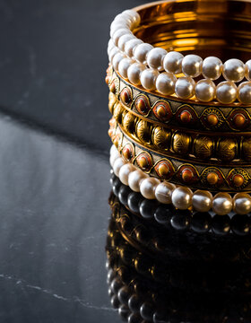 Stack of Pearl and Meenakari Gold Bangles Arranged on Dark Reflective Marble, Close-up of Traditional Indian Bridal Wedding Jewelry, Chura Ceremony, Karwa Chauth