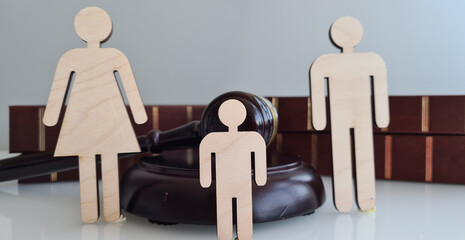 Wooden Figures Representing a Family Near a Gavel and Law Books