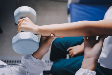 old woman training with physiotherapist using dumbbells at home therapist assisting senior woman with exercises in nursing home elderly patient using dumbbells with outstretched arms no logos no bran