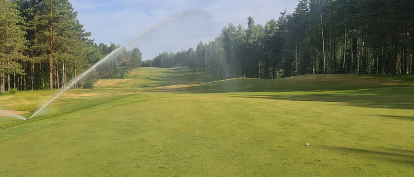 Sprinkler System Watering Golf Course Green on Sunny Day