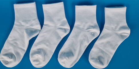 Four White Crew Socks Arranged on a Blue Background