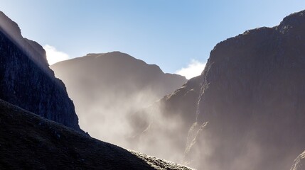 Mountain landscape, misty and sunlit, with rocky peaks under a clear blue sky, scenic view, copy space