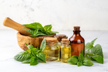Basil essential oil and fresh leaves on wooden table, closeup