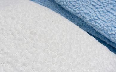 A detailed close-up view of textured white and blue towels. The image highlights the soft, fluffy surface and fabric weave of the towels for textile or cleaning themes.