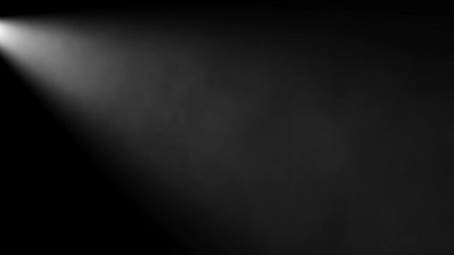 White light beam from top left spotlight effect shining through atmospheric smoke or dust particles on a dark black background with copy space