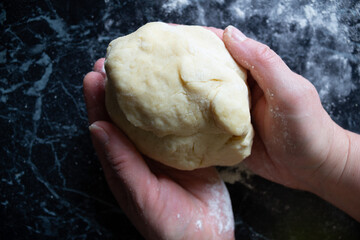 Female hands holding soft dough during the home baking process. Close-up. Rustic kitchen mood, fresh ingredients out of frame. Concept of pastry making and homemade food.
