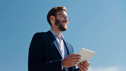 Happy entrepreneur checks tablet under clear blue, positive tech‑forward mood ideal for startups, personal branding, and ambitious career stories.