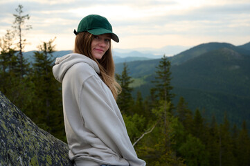 Woman traveler sitting on the rock at sunrise in the morning in the mountains. Solo camping. Solo female hiking. Cloudy morning view.