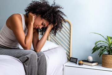 Woman experiencing stress, headache, and insomnia in bedroom