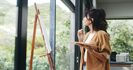 Woman, painting and thinking with canvas, easel or artwork for drawing or creative sketching in home. Person, artistic or painter with brush, frame or color palette for skill or talent in house