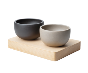Two textured bowls rest on a wooden block against a black backdrop