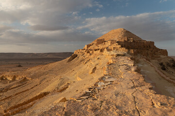 Scenic view of sun-drenched ancient abandoned Berber village of Ksar Guermessa with white mosque on arid hillsides