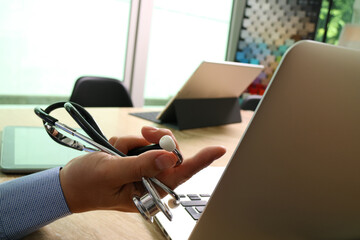 Doctor using laptop with stethoscope in modern office