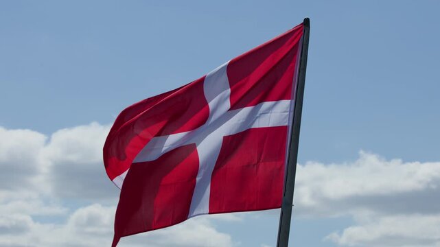 Danish Flag Waving in Wind Against Blue Sky