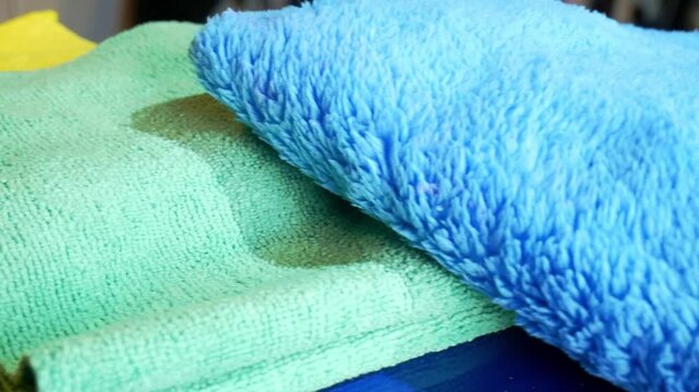 Left to right sliding shot of various microfiber towels in yellow, green and blue