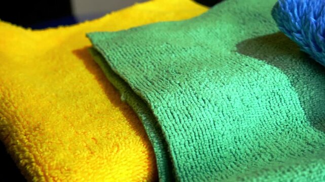 Close up left to right sliding shot of various microfiber towels in yellow, green and blue