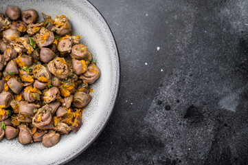 Tasty giblets stew served in gray plate on textured black surface ideal for culinary blogs or traditional meal visuals.