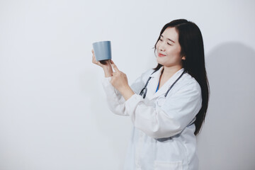 Portrait of Asian doctor woman standing holding coffee cup in white studio background