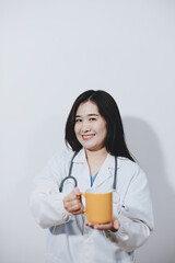 Portrait of Asian doctor woman standing holding coffee cup in white studio background