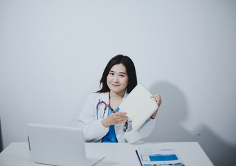 Middle aged female doctor working on laptop in doctor's room