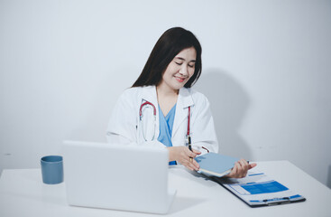 Middle aged female doctor working on laptop in doctor's room